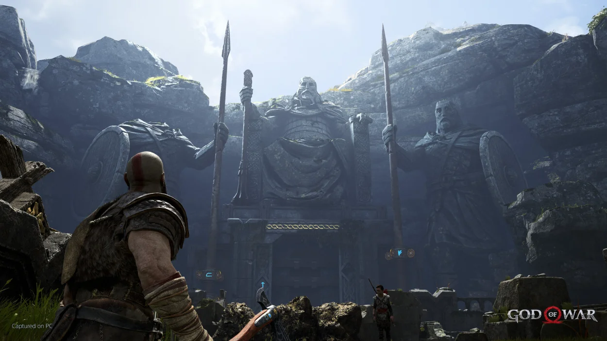 Kratos looking up at a massive stone statue flanked by spears